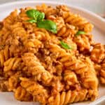 creamy beef pasta recipe served on a white plate and topped with fresh basil