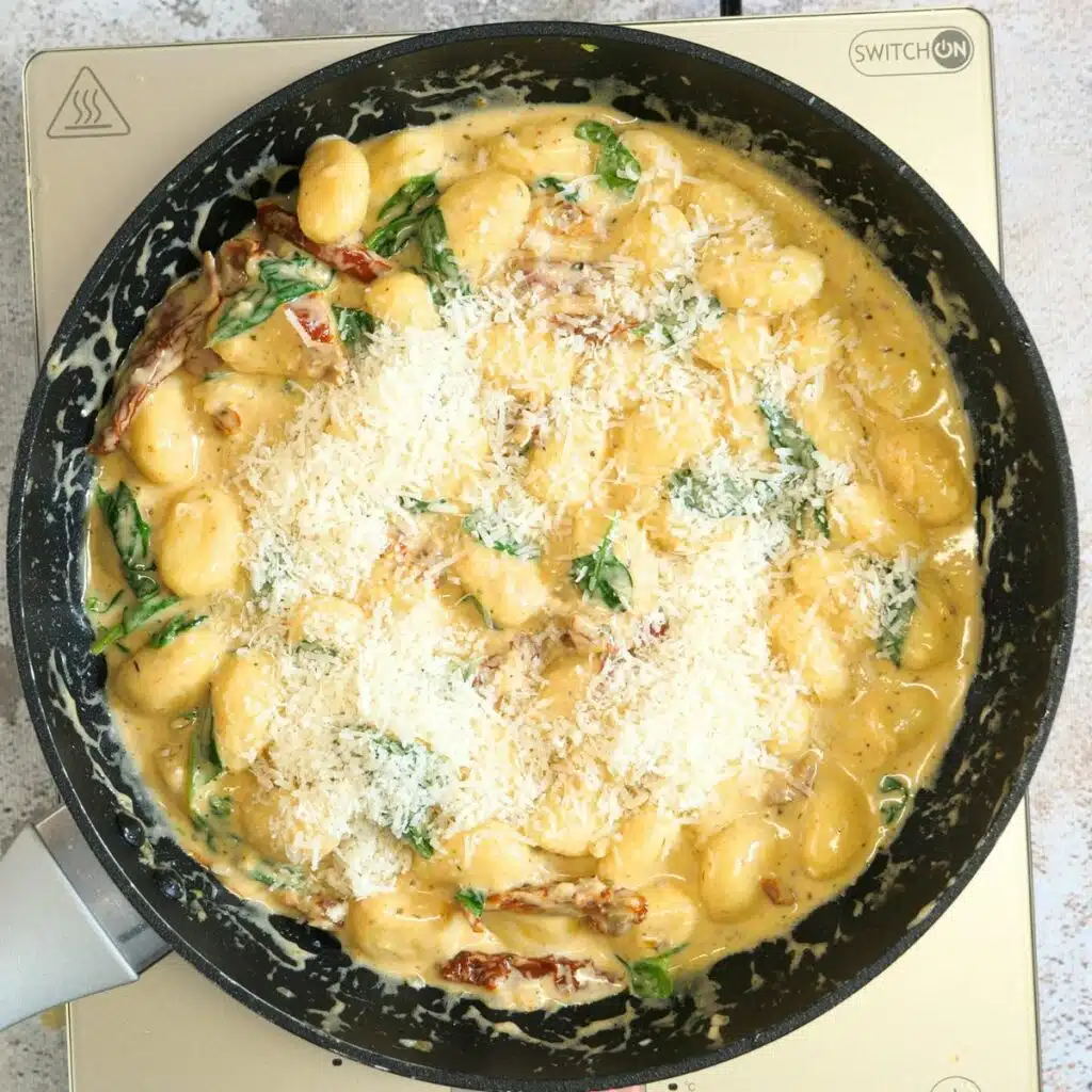 Creamy Tuscan Gnocchi Recipe 9 progress picture of adding freshly grated parmesan to the sauce