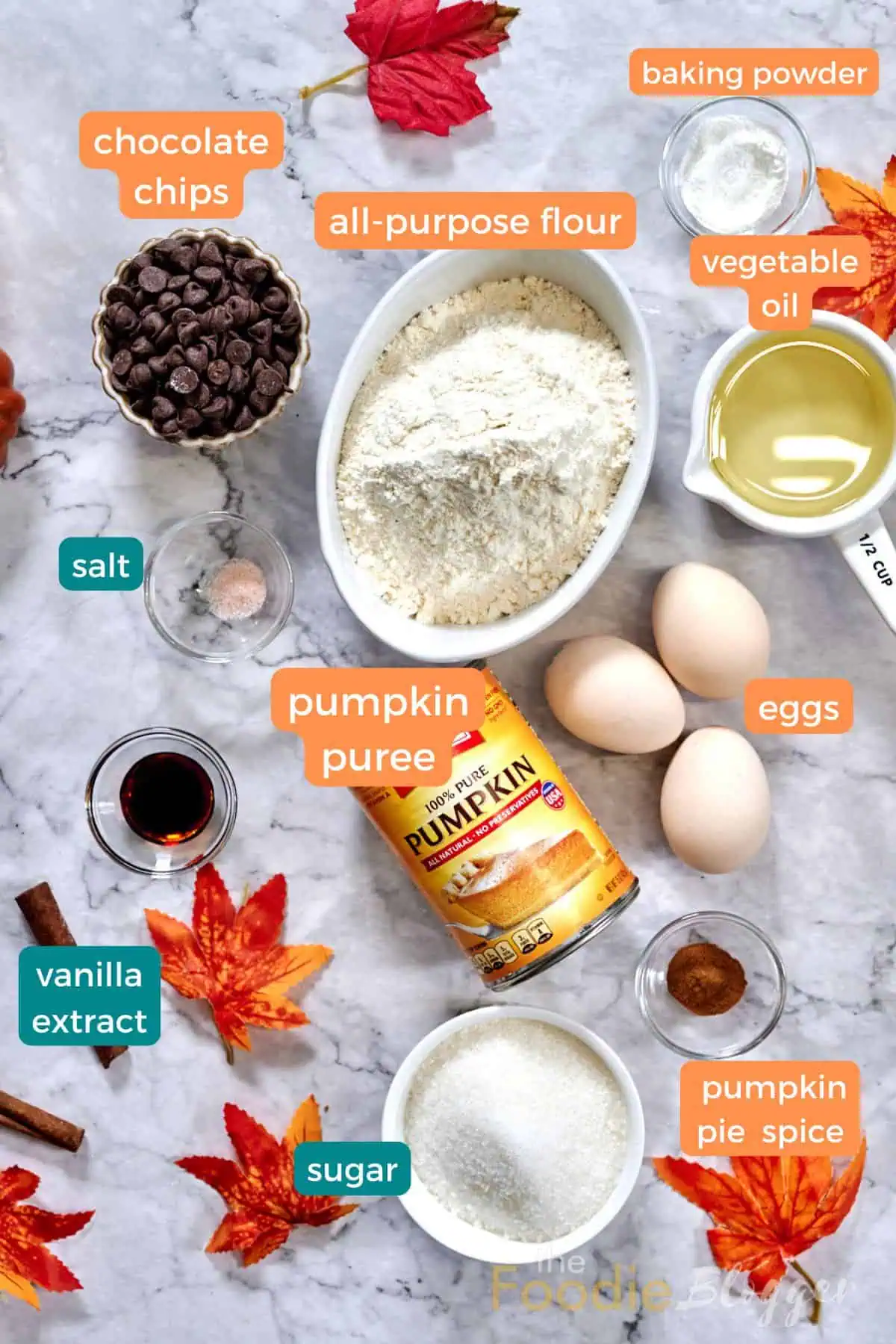 Ingredients for Easy Pumpkin Chocolate Chip Bread, including pumpkin puree, flour, eggs, chocolate chips, and pumpkin spice, laid out on a kitchen counter