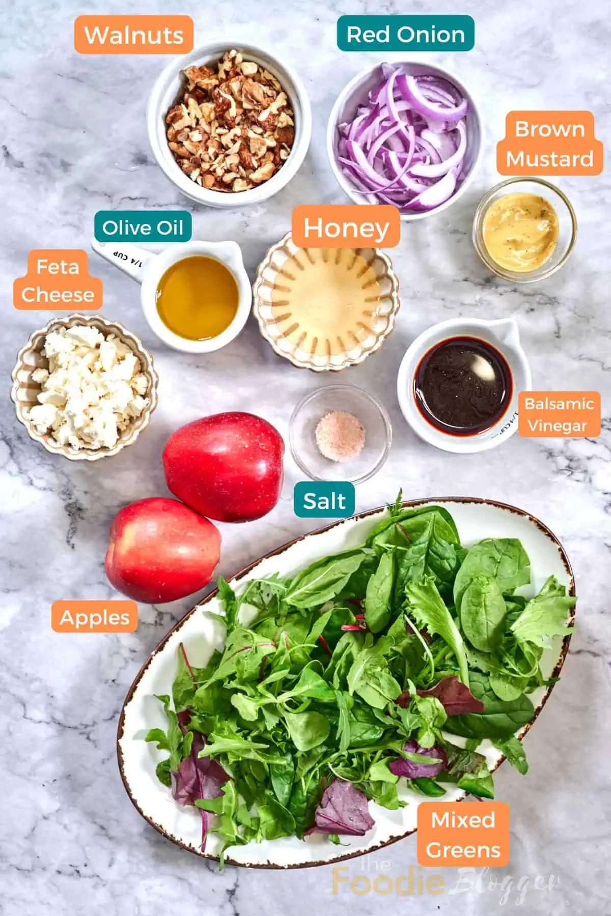 Apple Walnut Salad 3 Flat-lay of salad ingredients: mixed greens, red apples, walnuts, feta, red onion, honey, balsamic vinegar, mustard, olive oil, and salt.