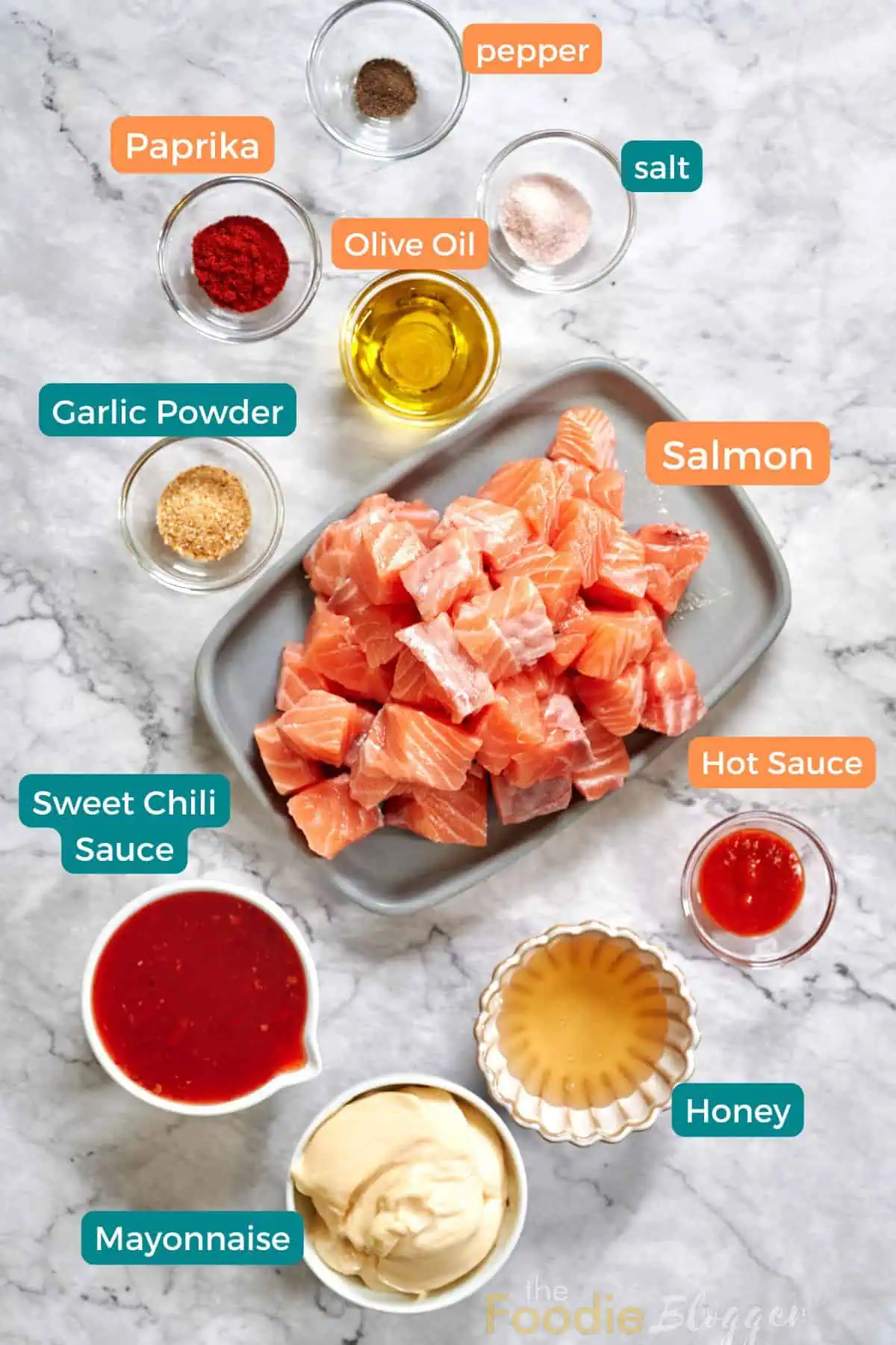 Bang Bang Salmon 3 Ingredients for bang bang salmon neatly arranged and labeled on a marble surface, including fresh salmon cubes, mayonnaise, sweet chili sauce, and spices.