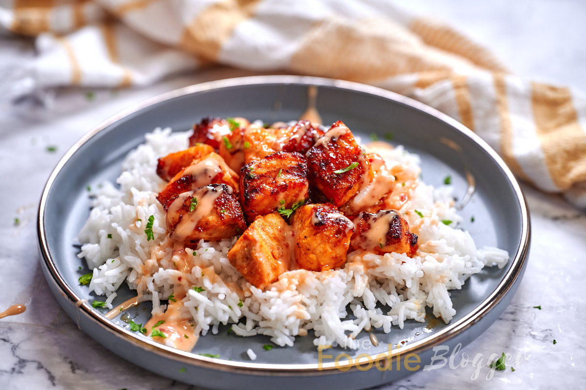 Bang Bang Salmon 9 Crispy, glazed salmon pieces resting on a bed of rice, drizzled with bang bang sauce.