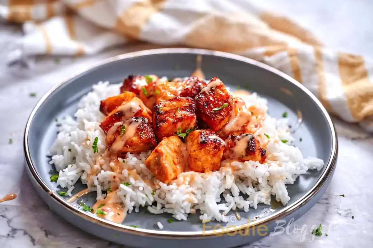 Bang Bang Salmon 9 Crispy, glazed salmon pieces resting on a bed of rice, drizzled with bang bang sauce.