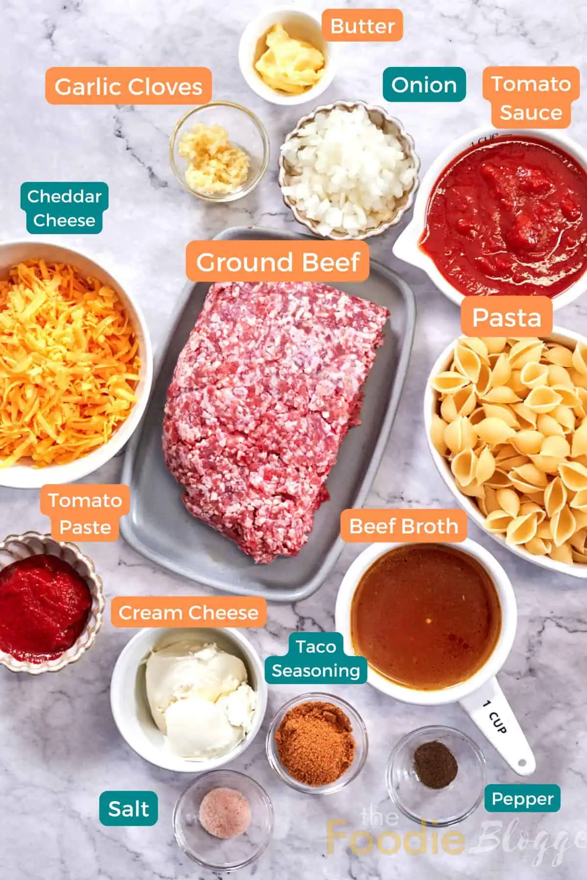 Cheesy Taco Pasta (One Pot) 3 Ingredients for one-pot cheesy taco pasta: ground beef, shell pasta, tomato sauce and paste, shredded cheddar, cream cheese, beef broth, diced onion, minced garlic, butter, taco seasoning, salt and pepper.