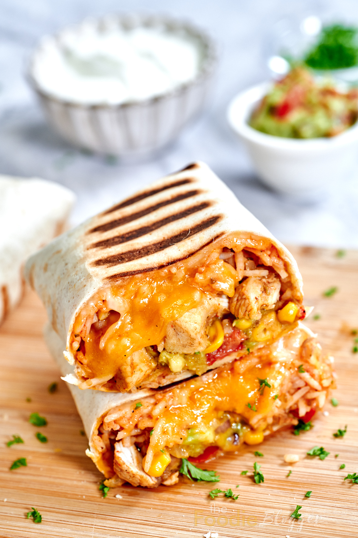 Chicken Burrito 10 Grilled tortilla ending cut cleanly to display the layered insides—rice, beans, corn, and chicken—set against stacked uncut burritos.