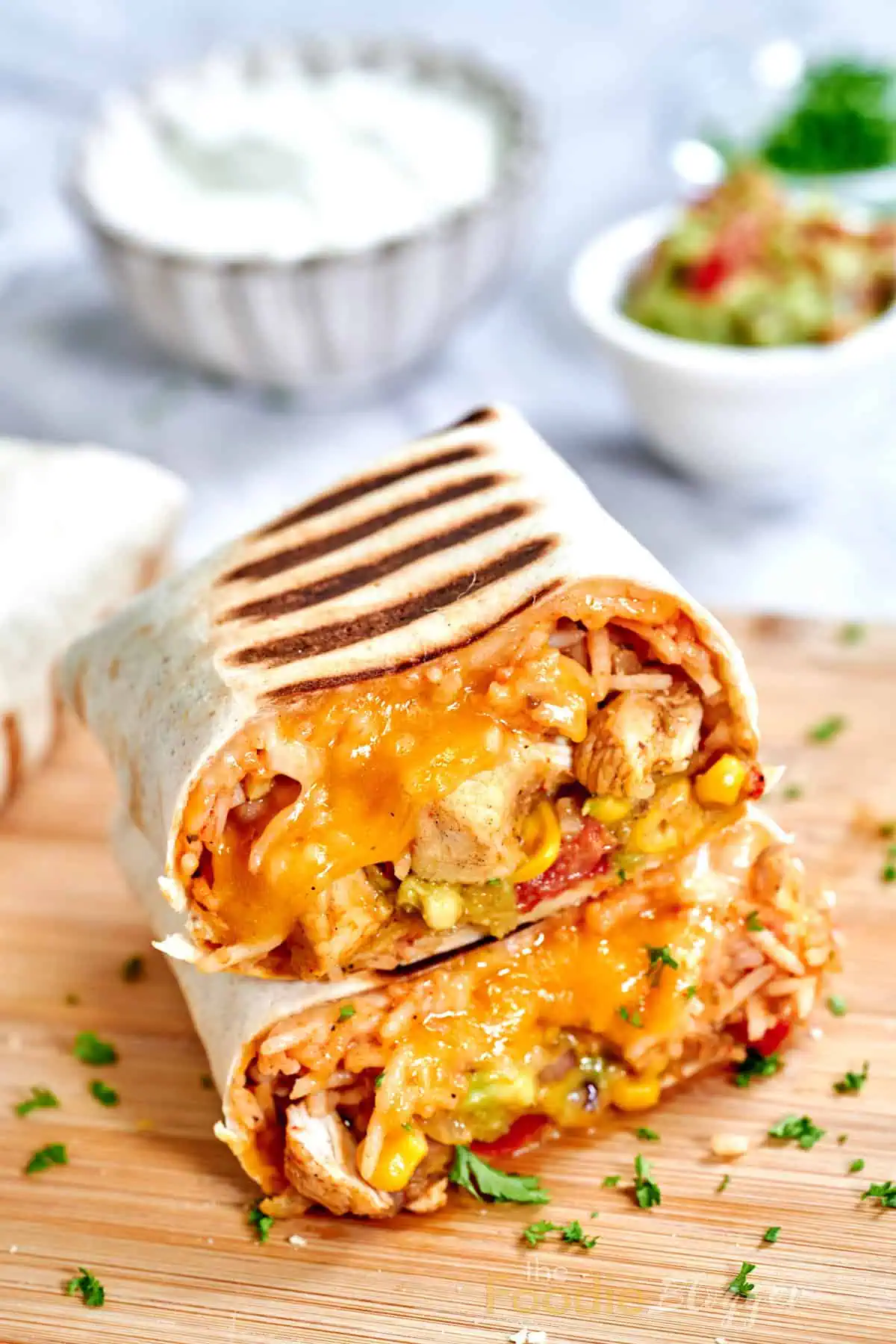 Chicken Burrito 10 Grilled tortilla ending cut cleanly to display the layered insides—rice, beans, corn, and chicken—set against stacked uncut burritos.