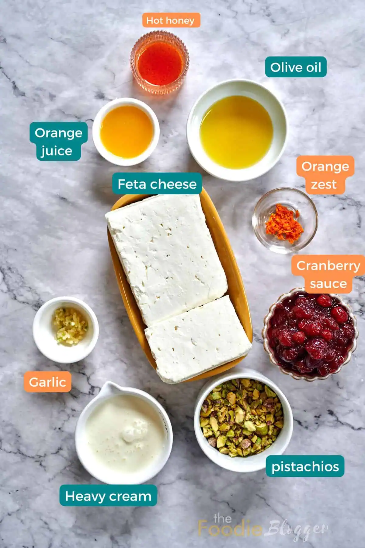 Cranberry Whipped Feta Dip 3 Ingredients for cranberry whipped feta dip neatly arranged on marble, including feta cheese, cranberry sauce, and pistachios.