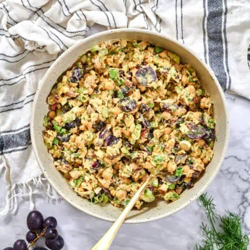 Vegan Chicken Salad 6 Overhead view of a large bowl of chickpea salad dotted with grapes, celery, and green onions, spoon ready for serving.