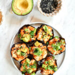 Overhead view of baked salmon sushi cups topped with avocado and sesame seeds.