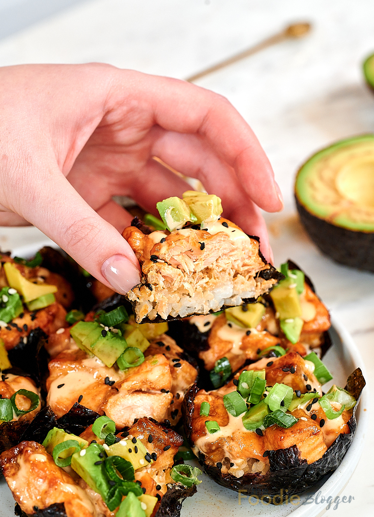 Baked Salmon Sushi Cups 12 Hand holding a baked salmon sushi cup showing rice, salmon, and avocado layers.
