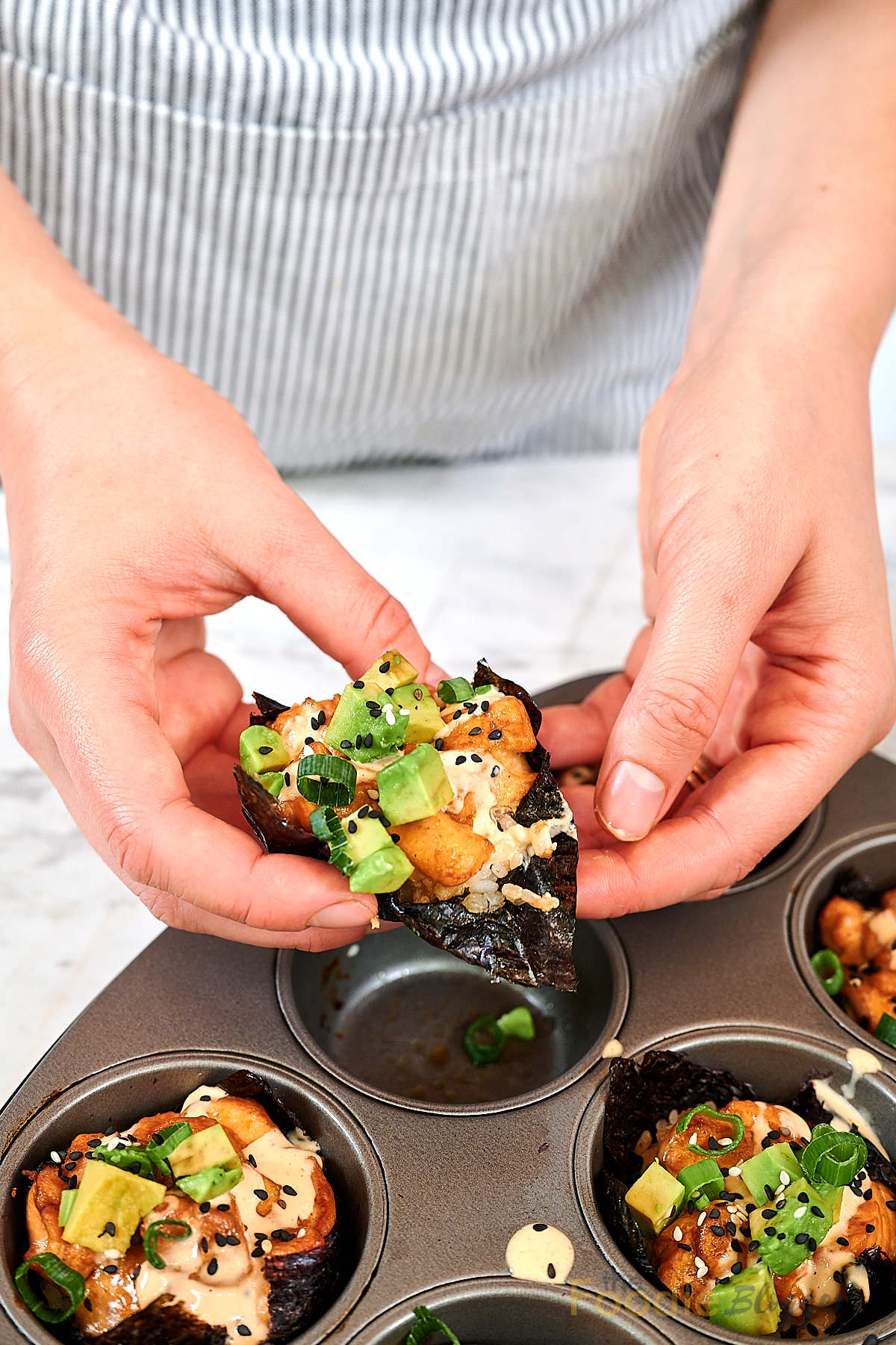 Baked Salmon Sushi Cups 13 Hands holding freshly baked salmon sushi cup lined with nori.