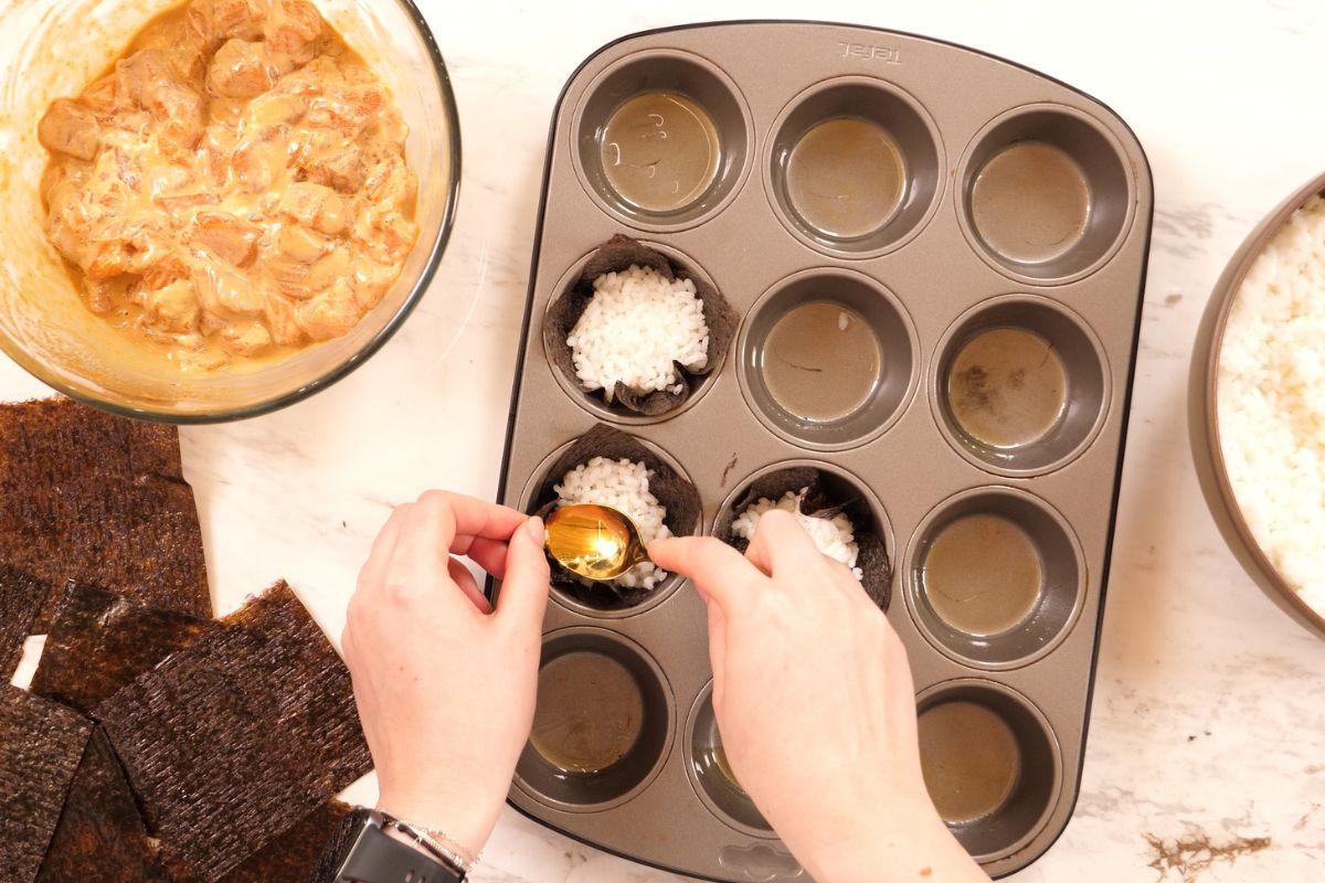 Baked Salmon Sushi Cups 7 Adding sushi rice to nori-lined muffin cups.