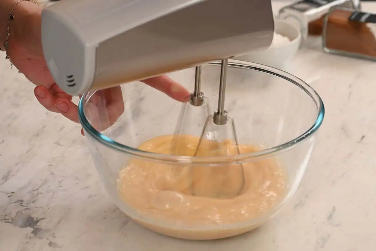 Invisible Apple Cake 5 Mixing eggs and sugar with an electric mixer to start the invisible apple cake batter.