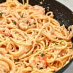 Close-up of ultra creamy garlic parmesan shrimp pasta in a skillet with tender shrimp and spaghetti tossed in a smooth garlic parmesan cream sauce