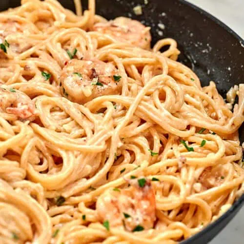 Ultra Creamy Garlic Parmesan Shrimp Pasta 15 Close-up of ultra creamy garlic parmesan shrimp pasta in a skillet with tender shrimp and spaghetti tossed in a smooth garlic parmesan cream sauce