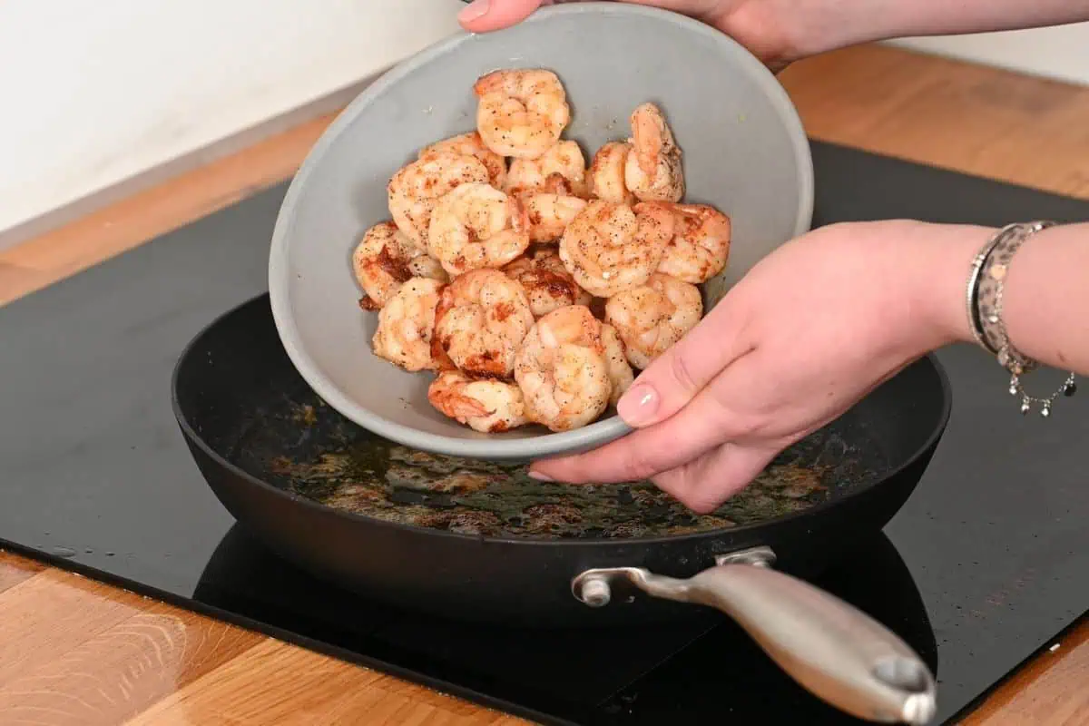 Ultra Creamy Garlic Parmesan Shrimp Pasta 5 Cooked shrimp being added back into a skillet for ultra creamy garlic parmesan shrimp pasta