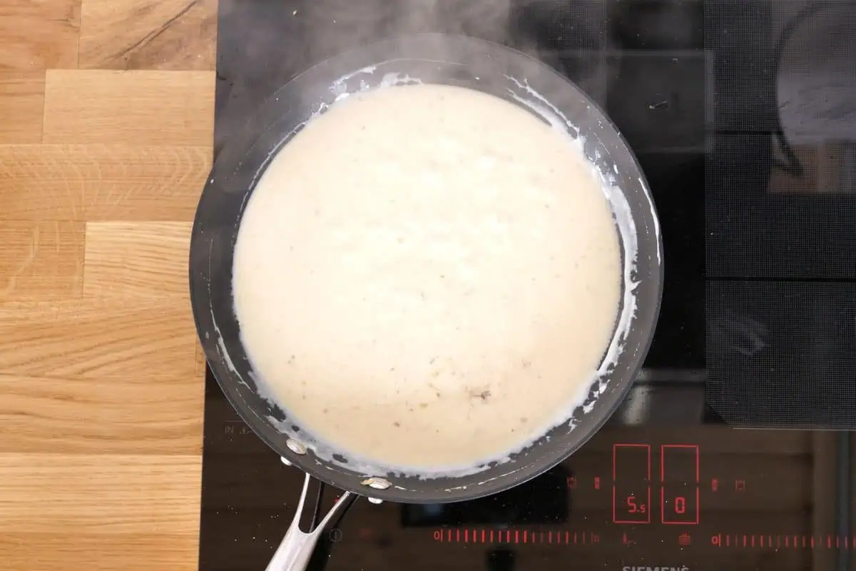 Ultra Creamy Garlic Parmesan Shrimp Pasta 9 Garlic parmesan cream sauce simmering in a skillet until thick and smooth