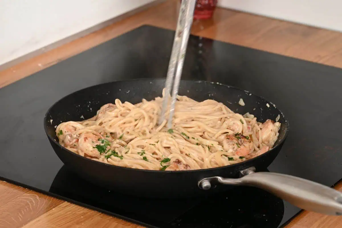 Ultra Creamy Garlic Parmesan Shrimp Pasta 12 Ultra creamy garlic parmesan shrimp pasta being tossed in a skillet until evenly coated