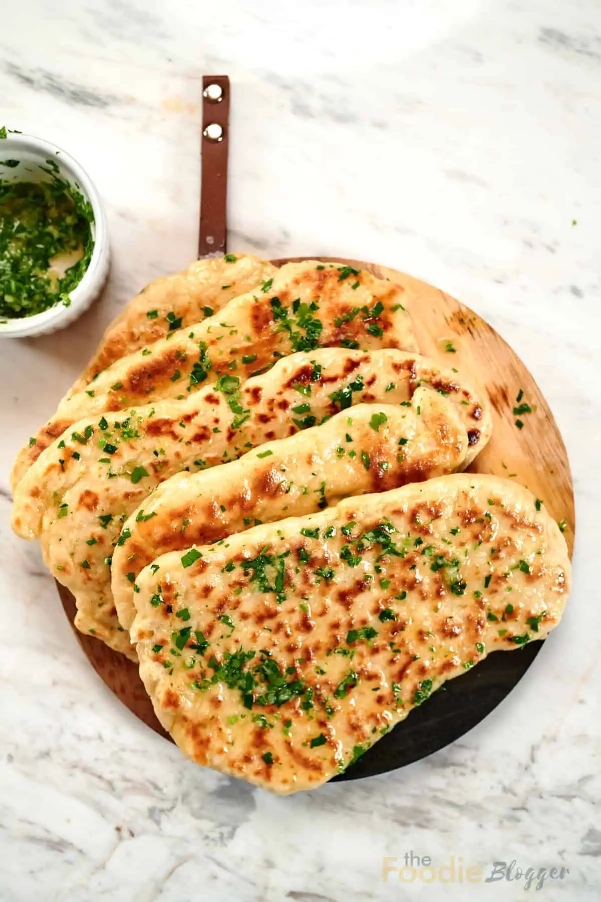 2-Ingredient Garlic Butter Naan 2 Stack of homemade 2-ingredient garlic butter naan brushed with garlic herb butter on a wooden serving board.