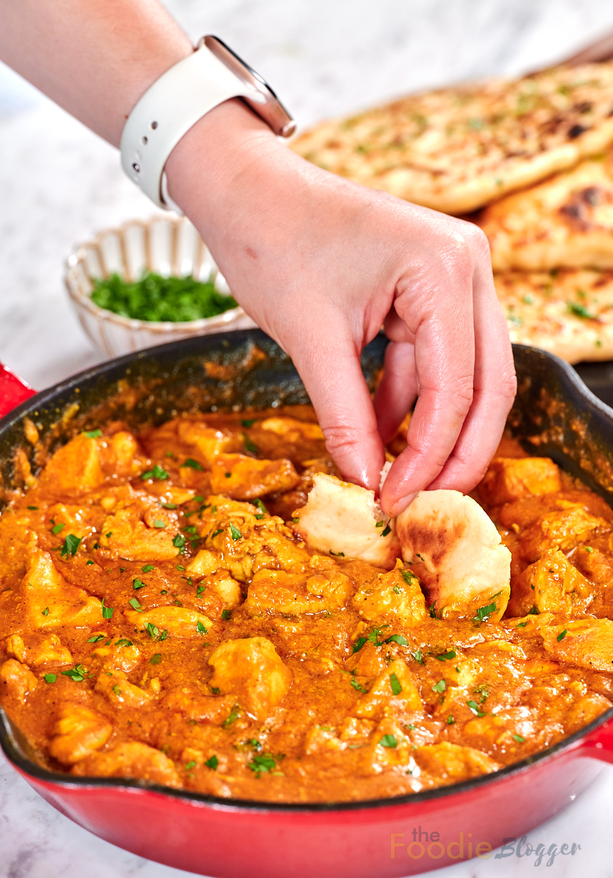 Creamy Chicken Coconut Curry 12 Hand dipping a piece of naan bread into creamy chicken coconut curry in a skillet.