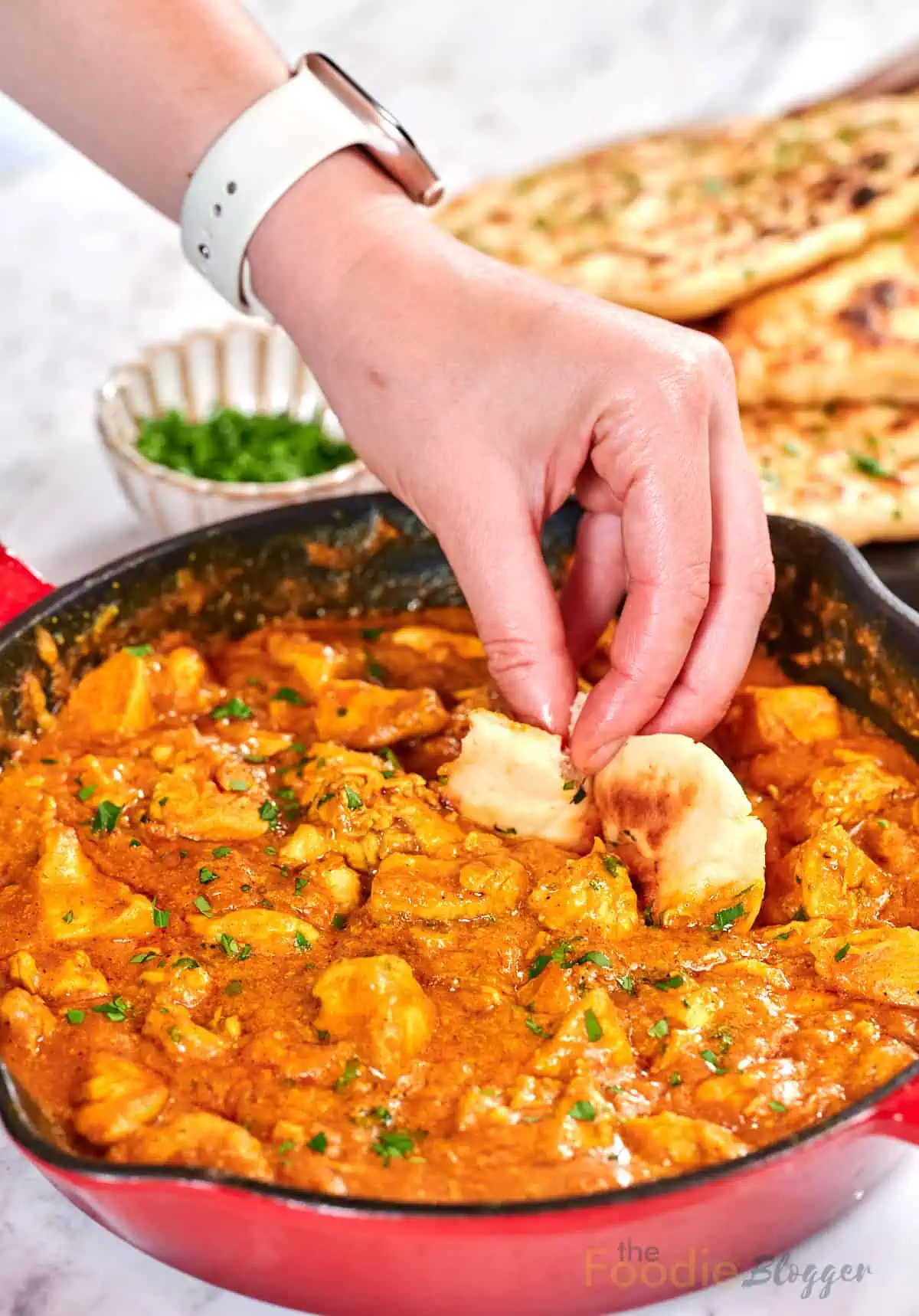 Creamy Chicken Coconut Curry 12 Hand dipping a piece of naan bread into creamy chicken coconut curry in a skillet.