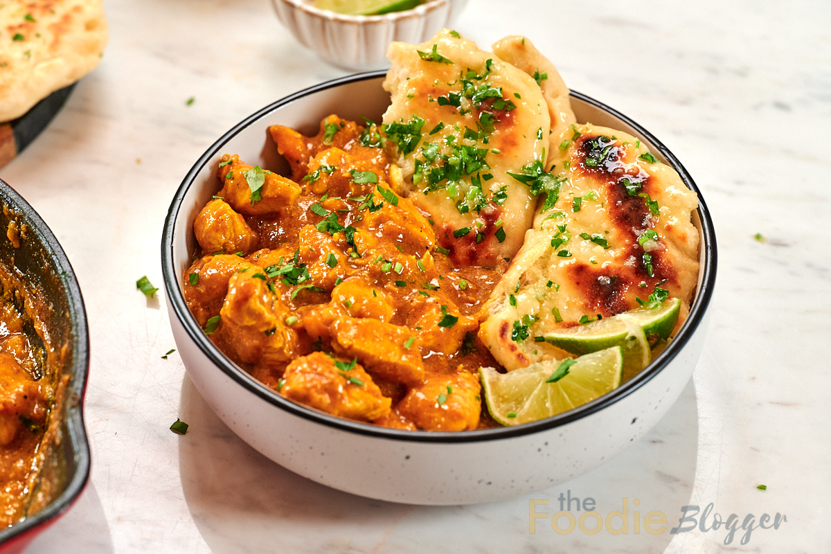 Creamy Chicken Coconut Curry 13 Close-up bowl of creamy chicken coconut curry served with garlic naan and fresh lime wedges.