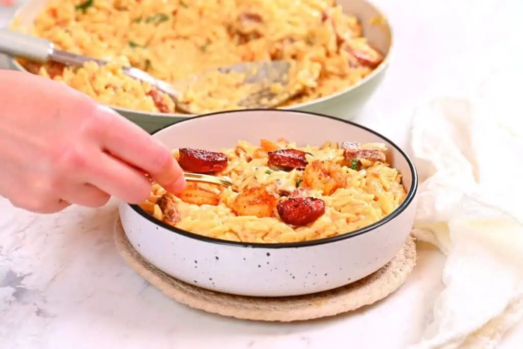 Creamy Cajun Shrimp Orzo 14 Serving creamy Cajun shrimp orzo in a bowl topped with shrimp and sausage slices.