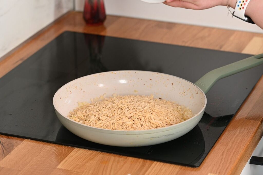 Creamy Cajun Shrimp Orzo 9 Adding uncooked orzo pasta to the skillet with sautéed onions.