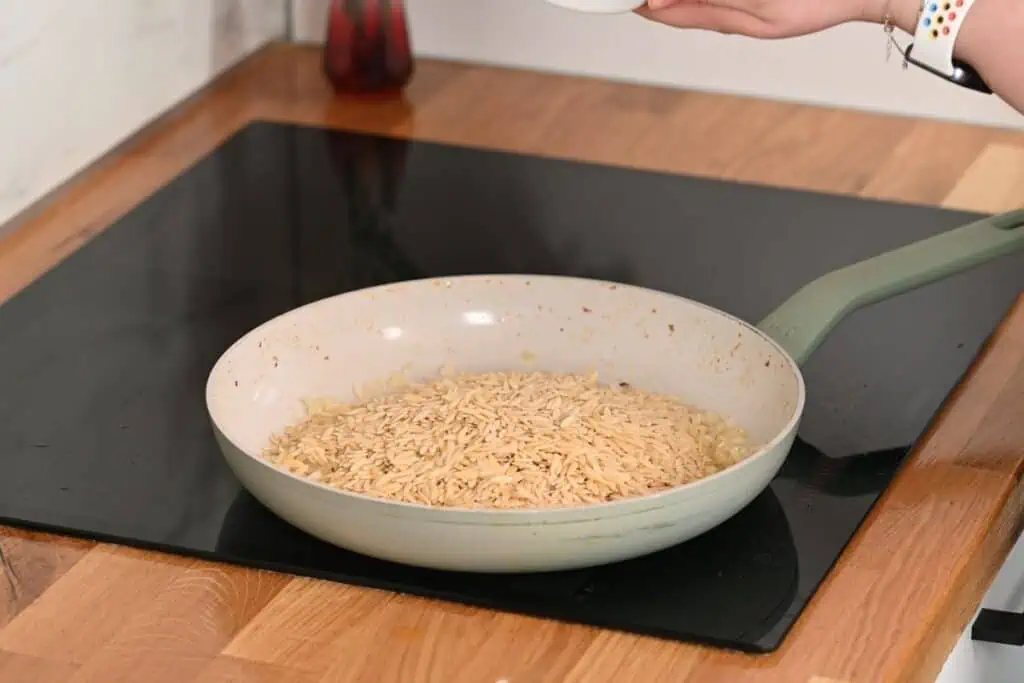 Creamy Cajun Shrimp Orzo 9 Adding uncooked orzo pasta to the skillet with sautéed onions.