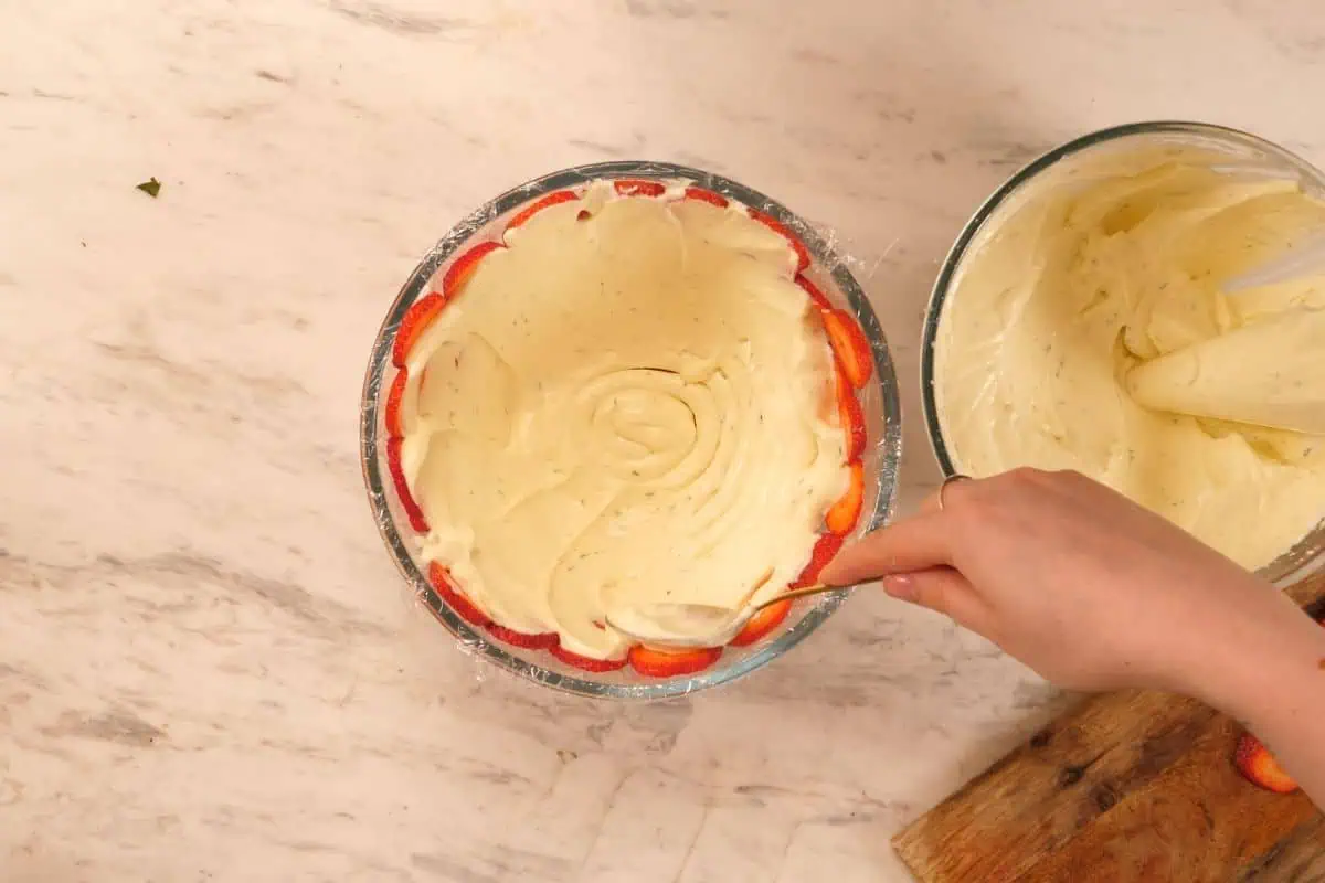 No-Bake Strawberry Lime Charlotte Cake 7 Creamy lime filling spread over the strawberry-lined bowl, creating the first layer of the Charlotte cake.
